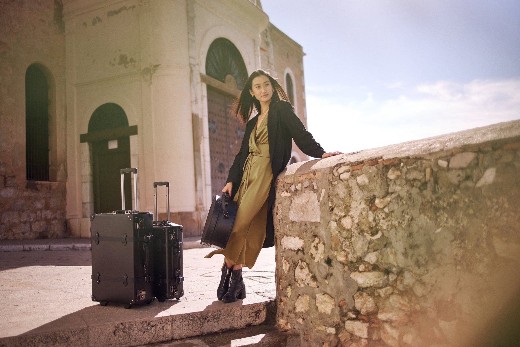 Lifestyle image of model with The Industrialist fibreboard suitcases in  black