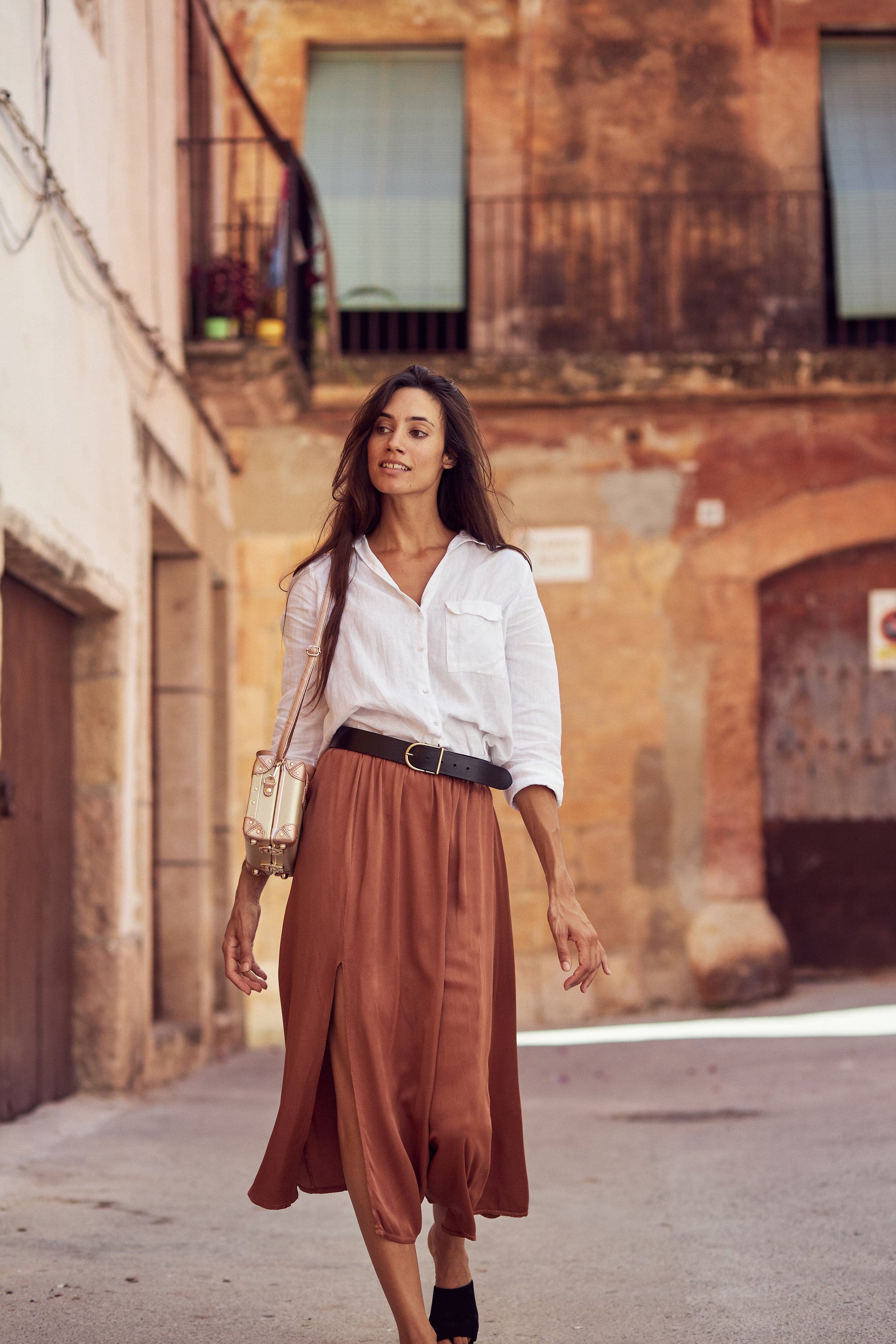 Lifestyle image of model with The Alchemist vegan leather mini  in gold with shoulder attachment strap