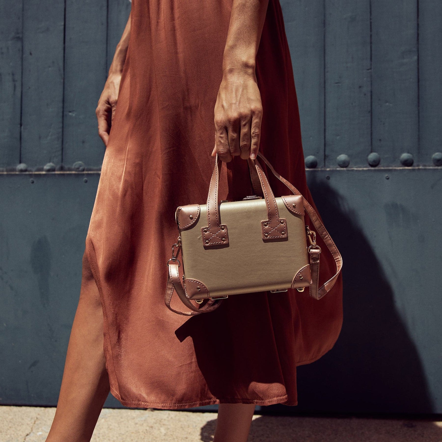 Lifestyle image of model with The Alchemist vegan leather mini handbag in gold