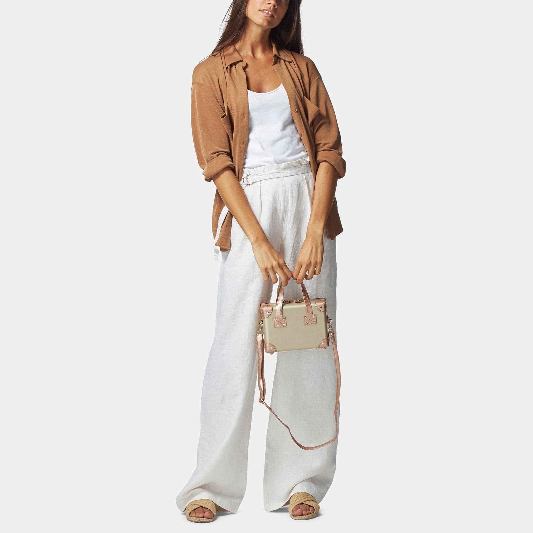 Model with the mini Alchemist vegan leather suitcase in gold with shoulder attachment strap