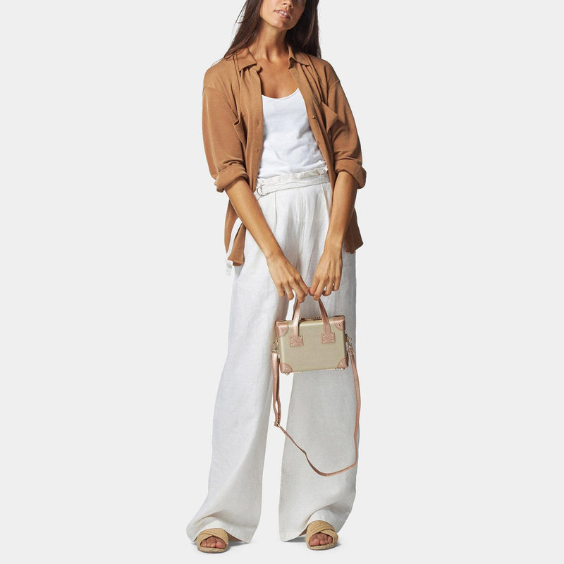 Model with the mini Alchemist vegan leather suitcase in gold with shoulder attachment strap