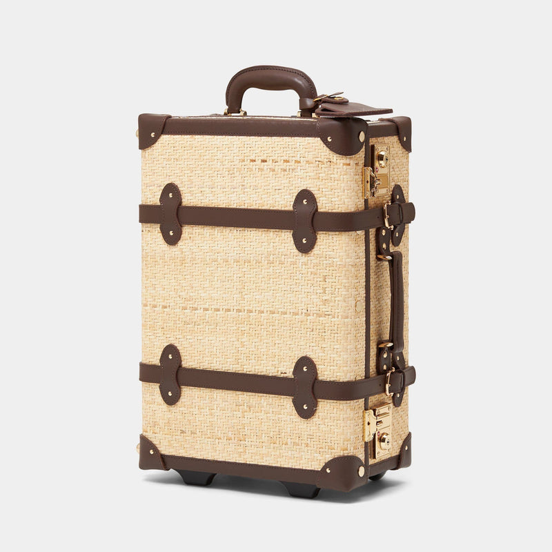 Angled product view of the carry-on Explorer rattan suitcase in natural wicker body and brown trims