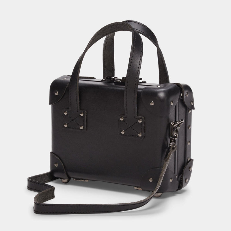 Angled product view of the mini Industrialist fibreboard suitcase in black with shoulder attachment strap