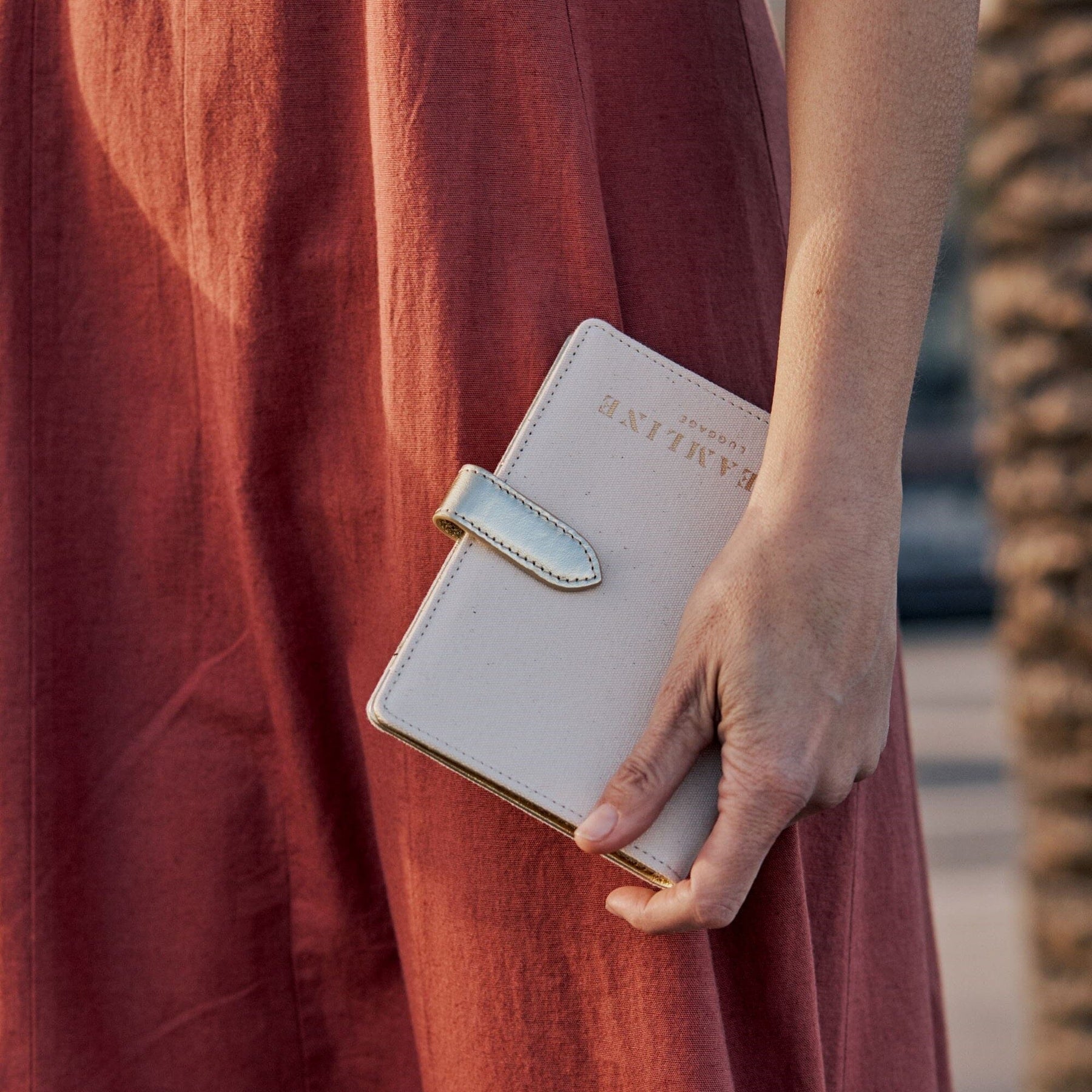 Lifestyle close up image of model with the Navigator passport holder in white with gold trim