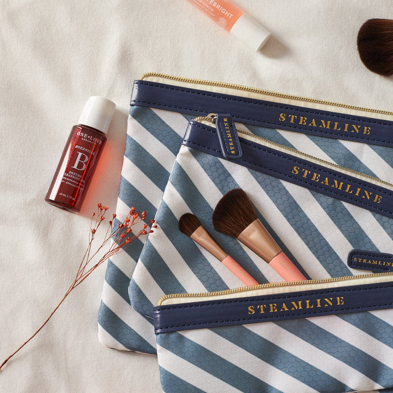 close up of set of three blue stripe cosmetic cases with makeup items