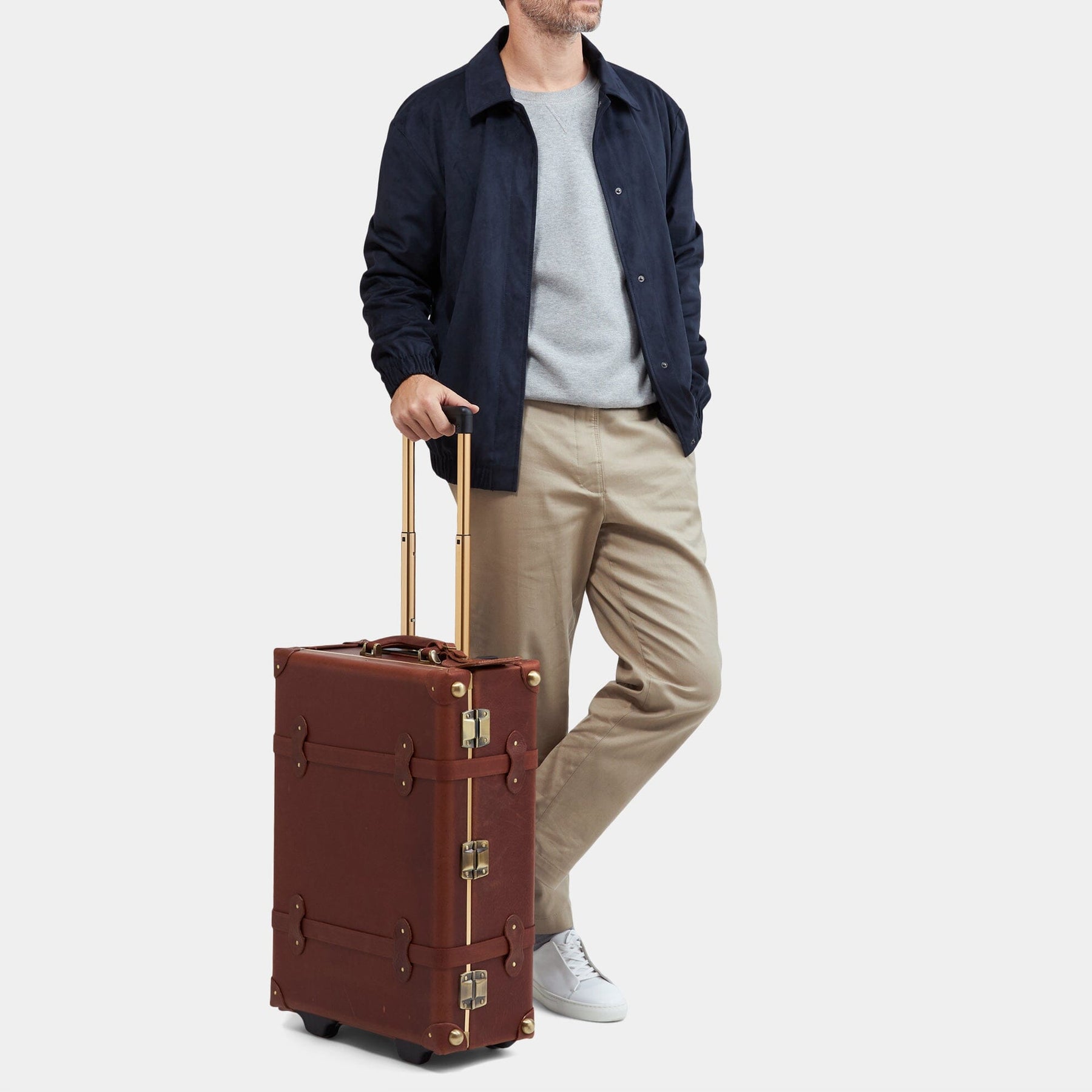 Male model with the stowaway Pioneer leather suitcase in brown with raised handle