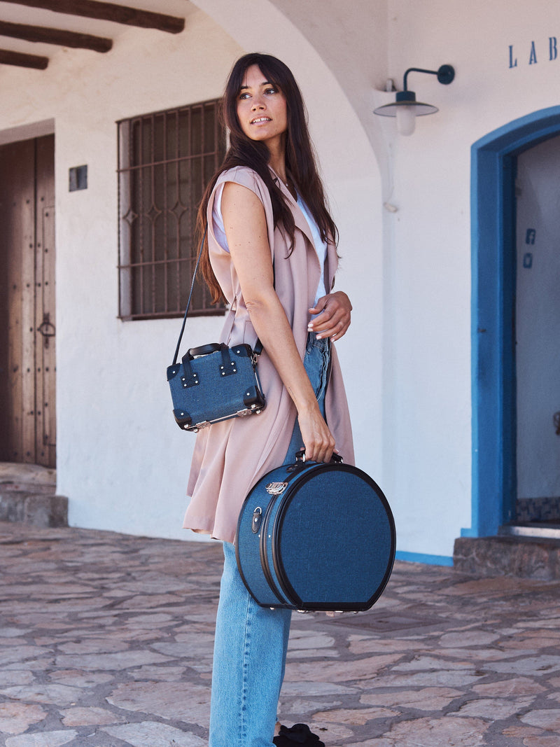 Lifestyle image of model with the Editor linen suitcases with navy body and black trims