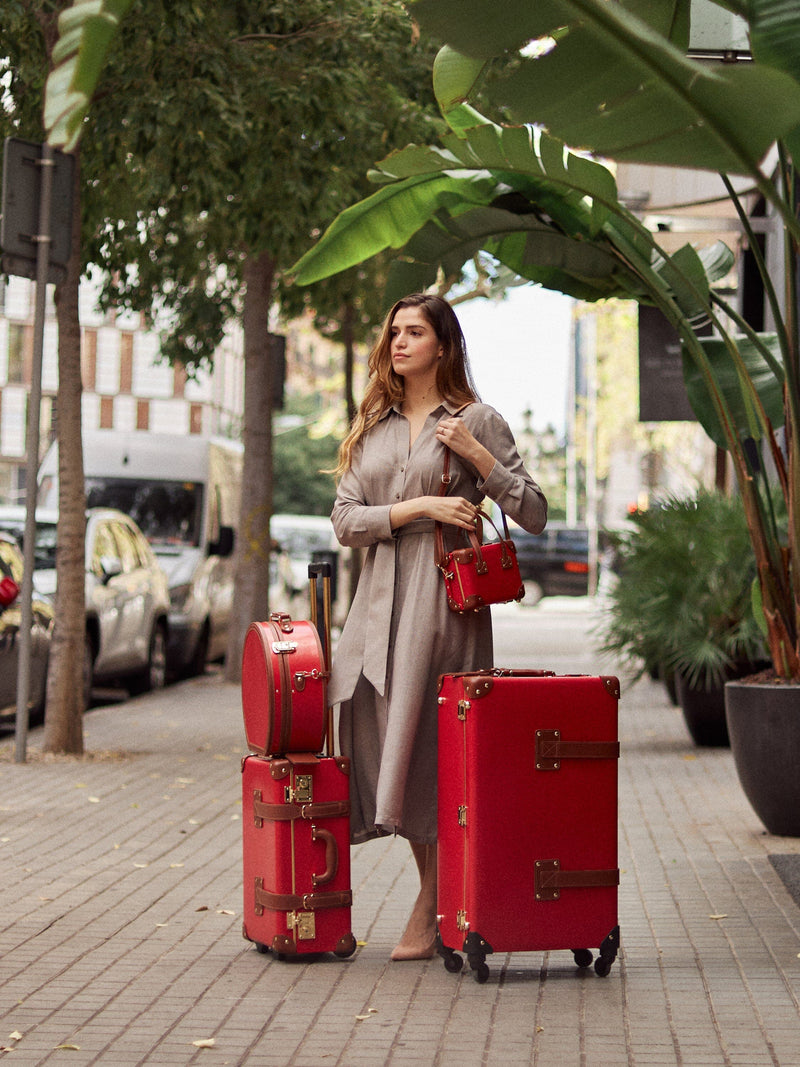 Lifestyle image of model with The Diplomat leather suitcases in red