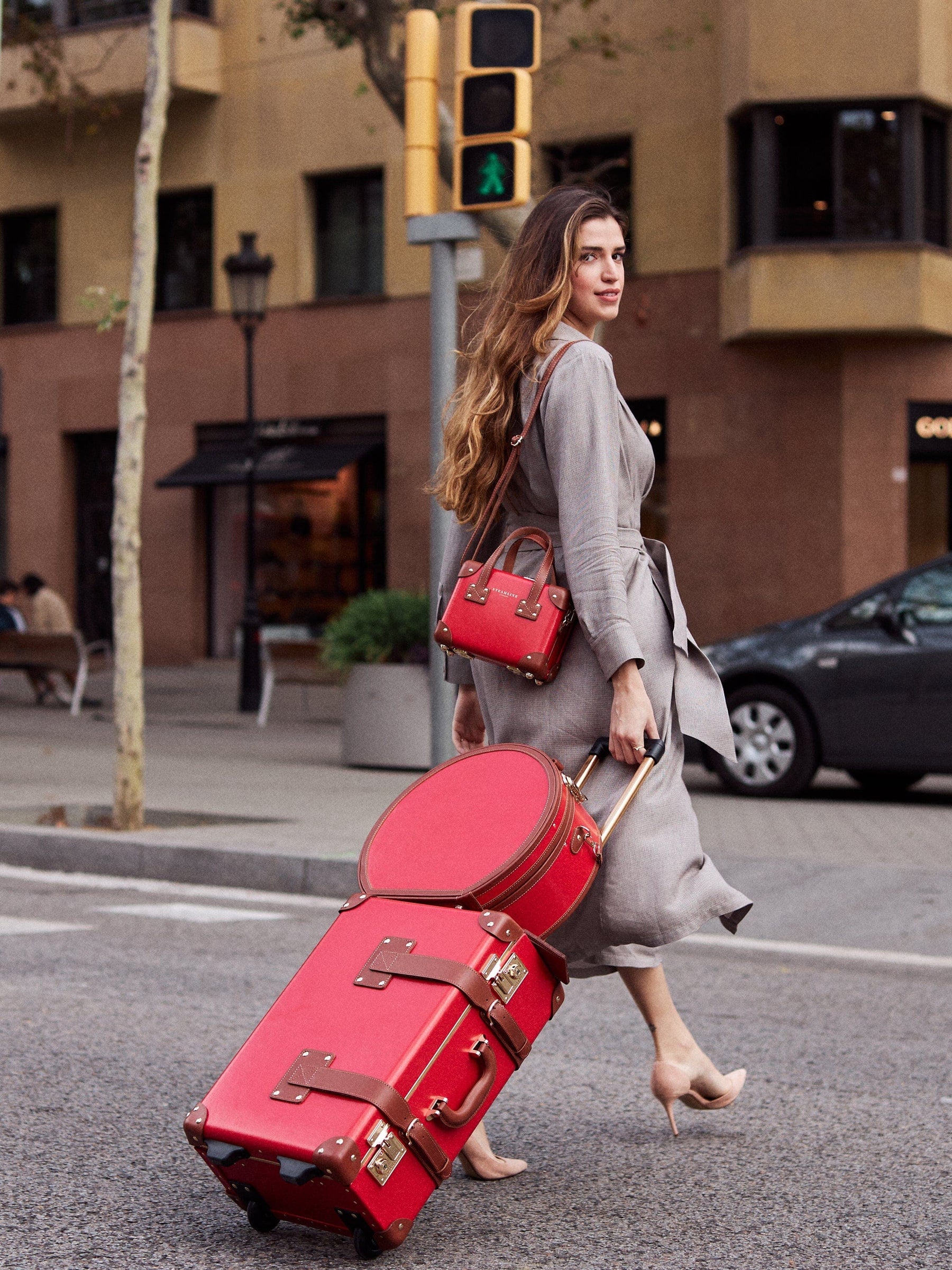 Lifestyle image of model with The Diplomat leather suitcases in red