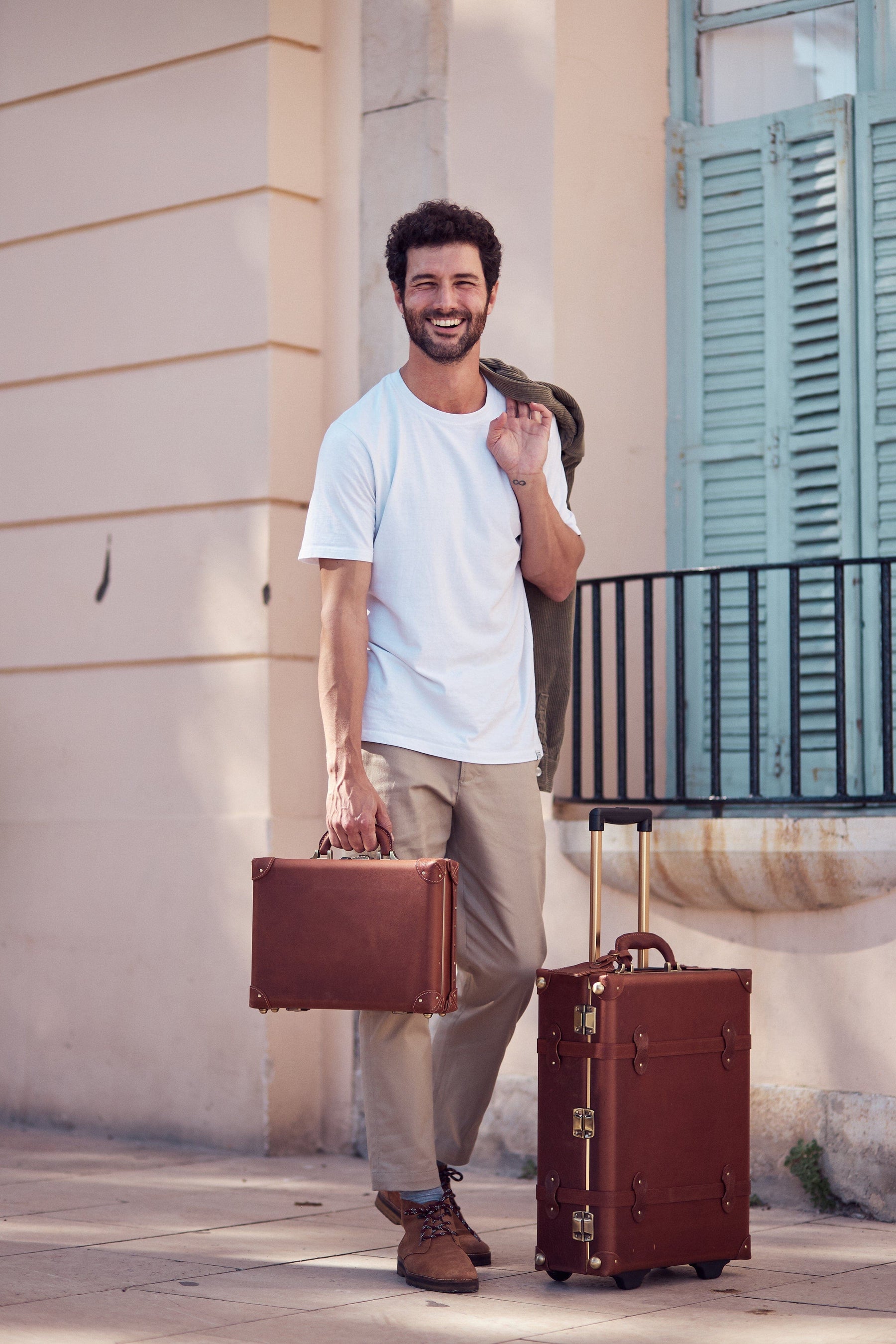 Lifestyle image of male model with The Pioneer leather suitcases in brown