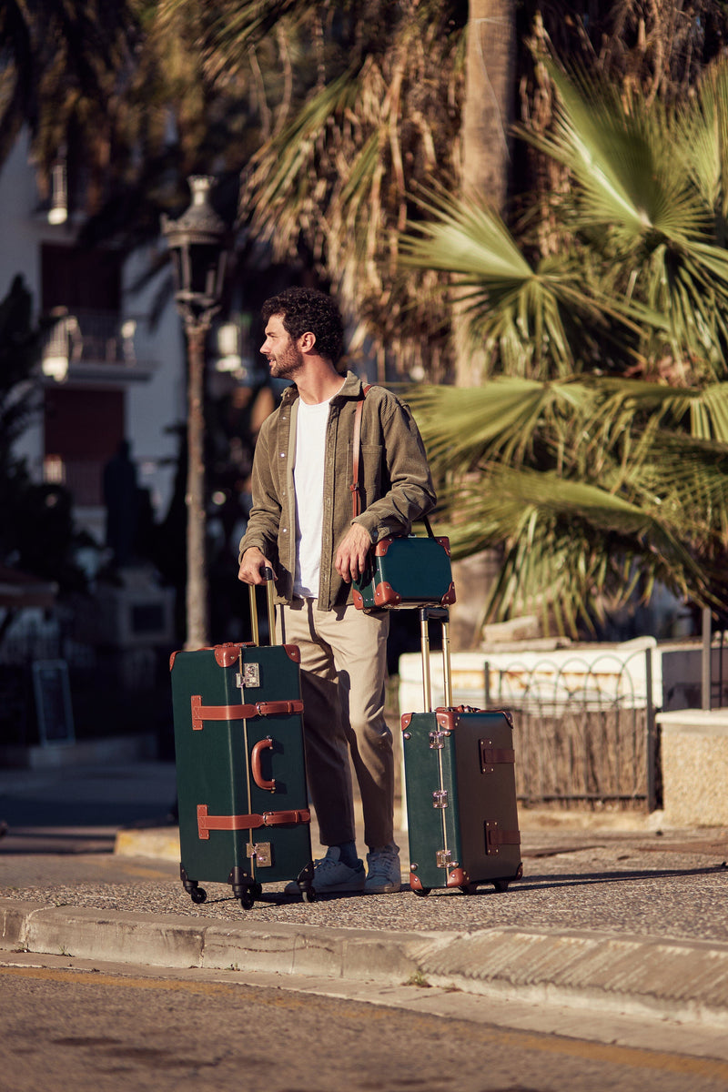 Lifestyle image of male model with the Diplomat leather suitcases in hunter green with raised handle