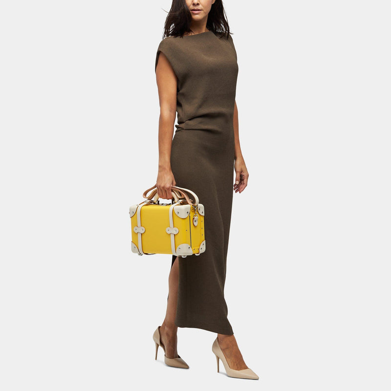 Model with the vanity Correspondent fibreboard suitcase in yellow with shoulder attachment strap