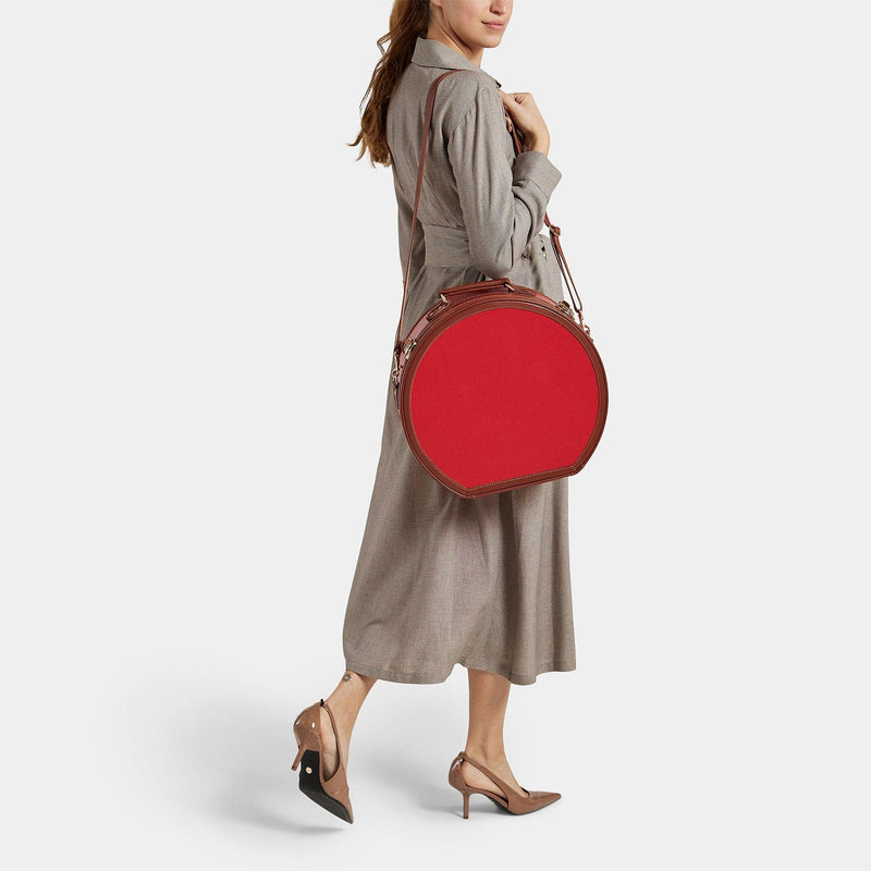 Model with the large hatbox Diplomat leather suitcase in red with shoulder attachment strap