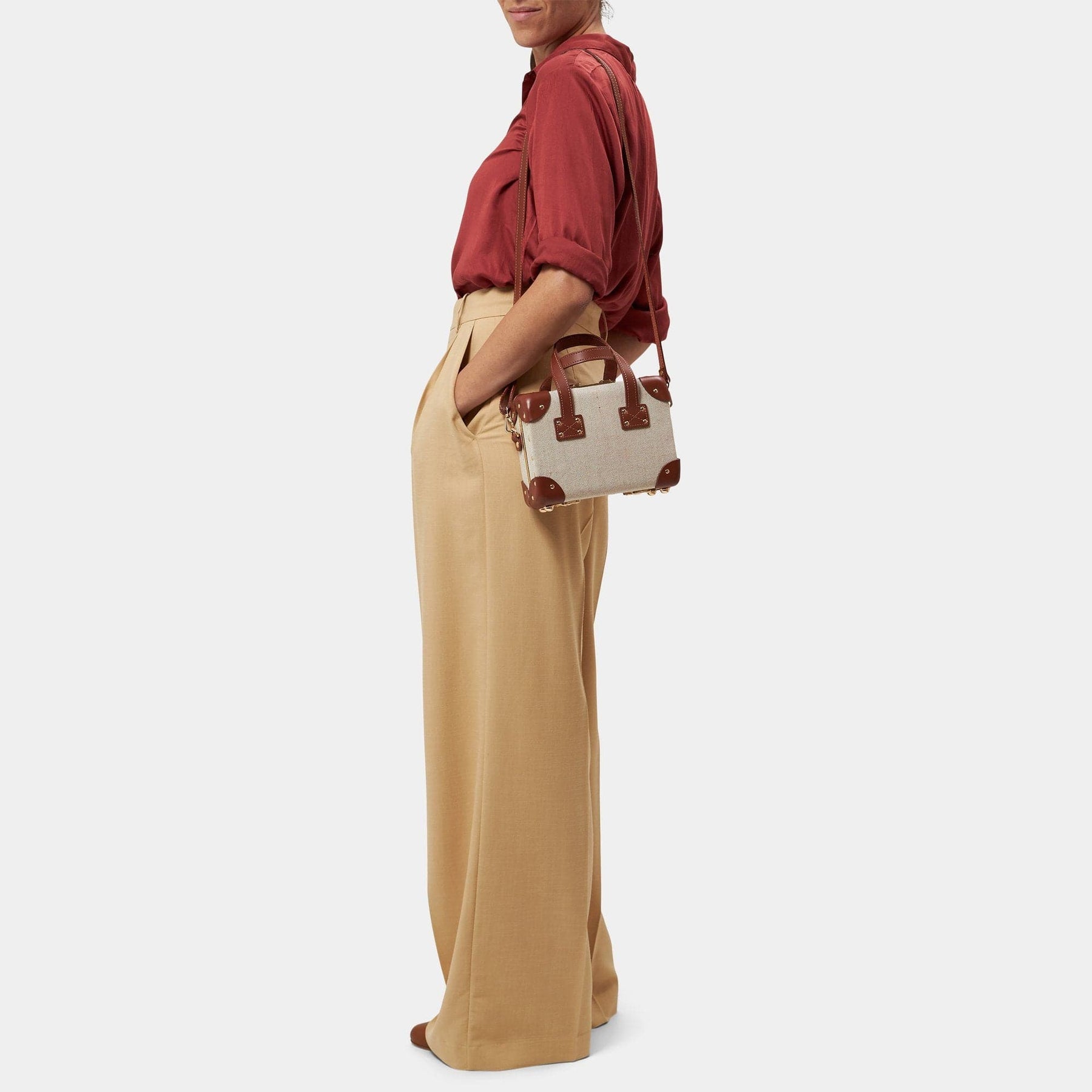 Model with the mini Editor linen suitcase with brown trims and shoulder attachment strap