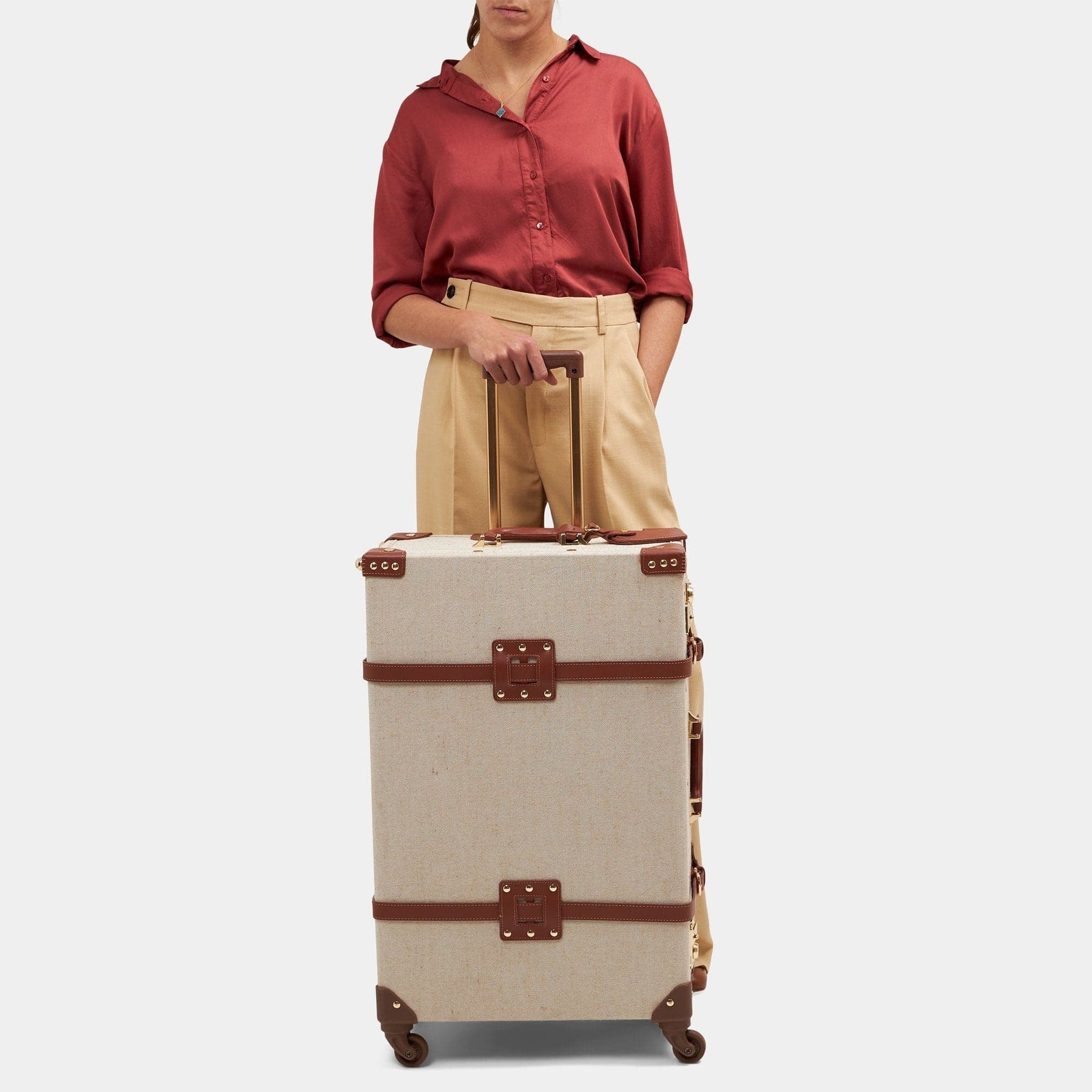 Model with the check-in spinner Editor linen suitcase with brown trims and raised handle