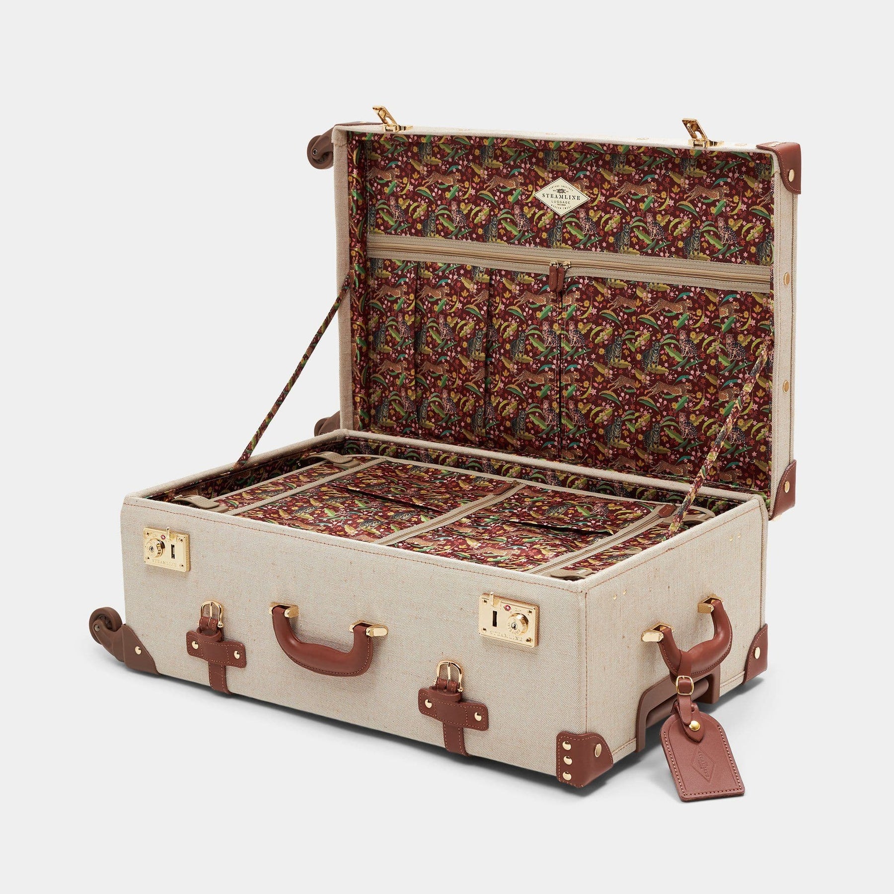 Open product view of the check-in spinner Editor linen suitcase with brown trims, exotic-bird print lining and leather luggage tag