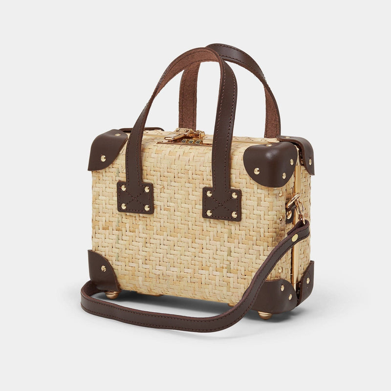 Angled product view of the mini Explorer rattan suitcase in natural wicker body and brown trims with shoulder attachment strap