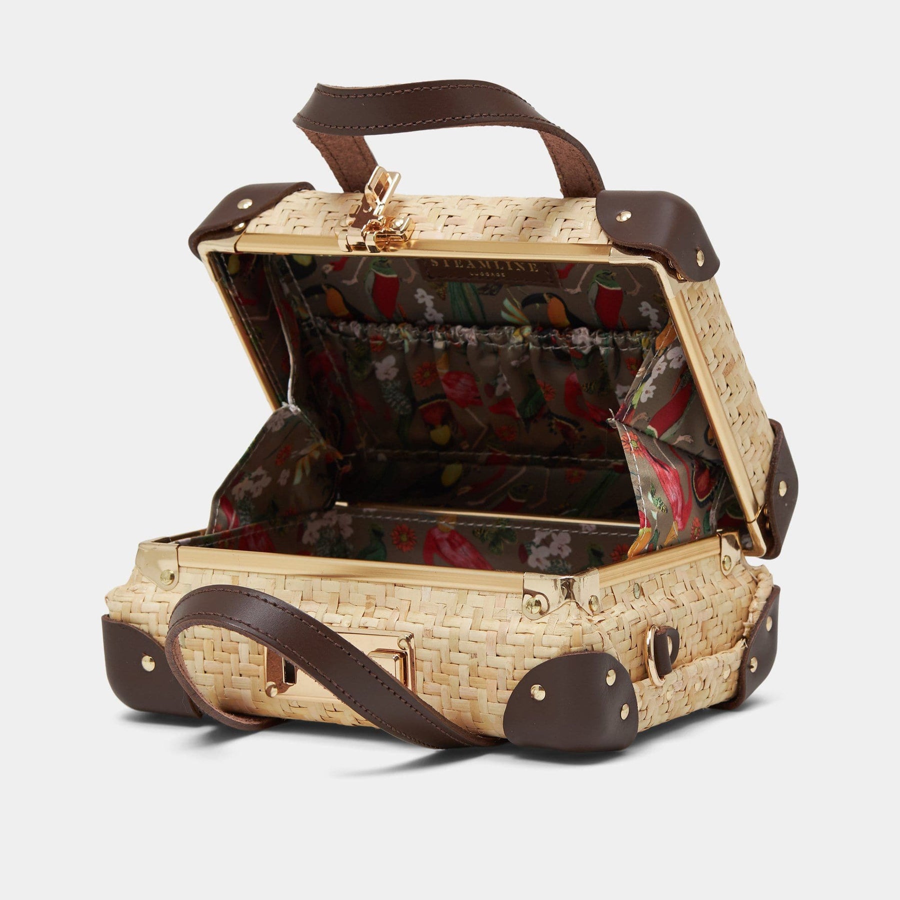 Open product view of the mini Explorer rattan suitcase in natural wicker body and brown trims with exotic bird print lining