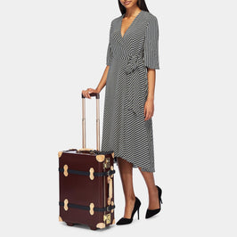 Model with the carry-on Architect leather suitcase in burgundy with raised handle