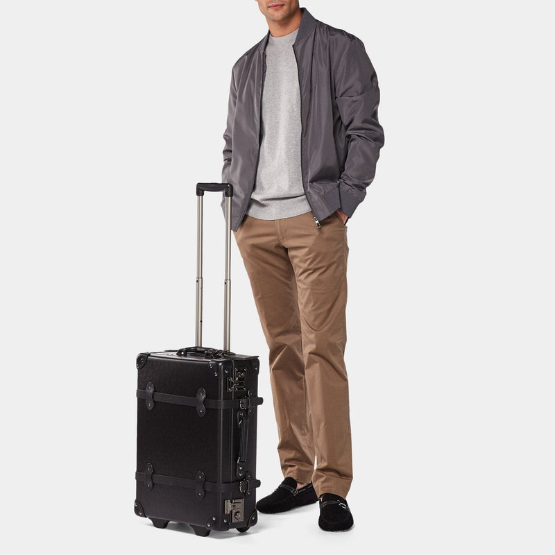Male odel with the carry-on Industrialist fibreboard suitcase in black with raised handle